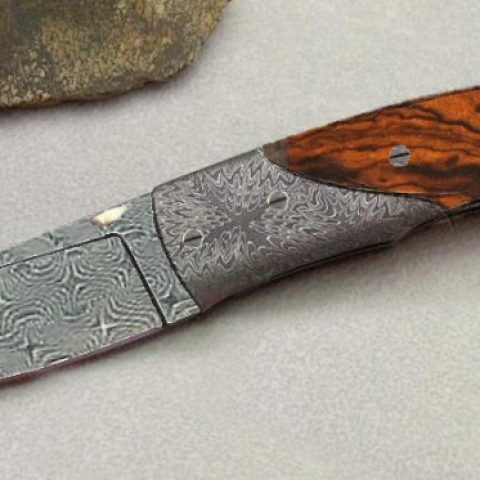 knife made with interlocking damascus pattern and dark wood handle
